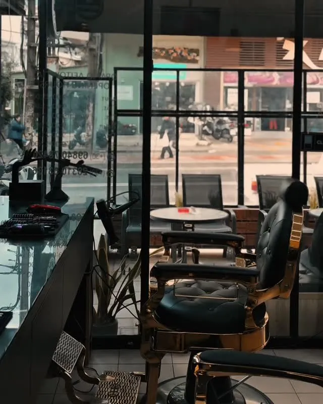 Inside Buzz Cuts Barbershop: a black chair with gold details in front of the shop window