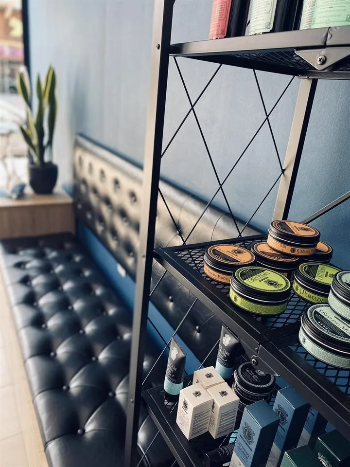 A shelf with pomades and face care creams next to the waiting sofa